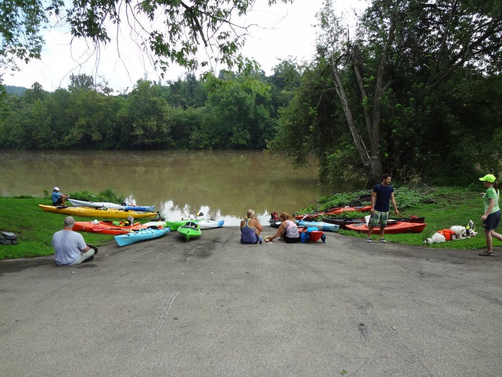 People gathering around a pond with their kayaks